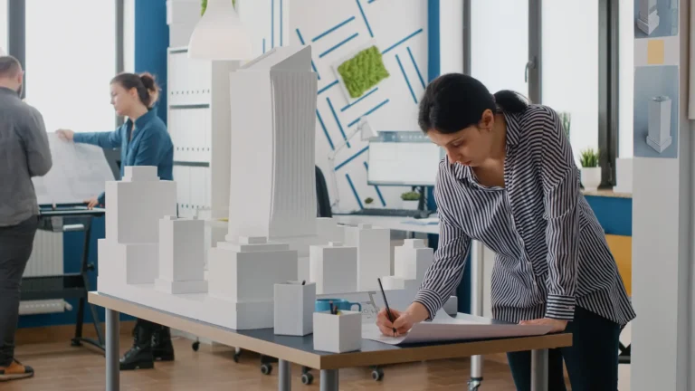 woman-architect-analyzing-blueprints-plan-table-design-building-model-maquette-engineer-working-architectural-development-project-with-industrial-construction-tools